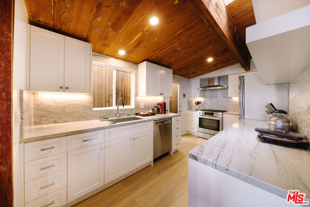 936 Palisades Beach Road Santa Monica, CA 90403 - Photo 6 of 31 a kitchen with granite countertop white cabinets and white appliances