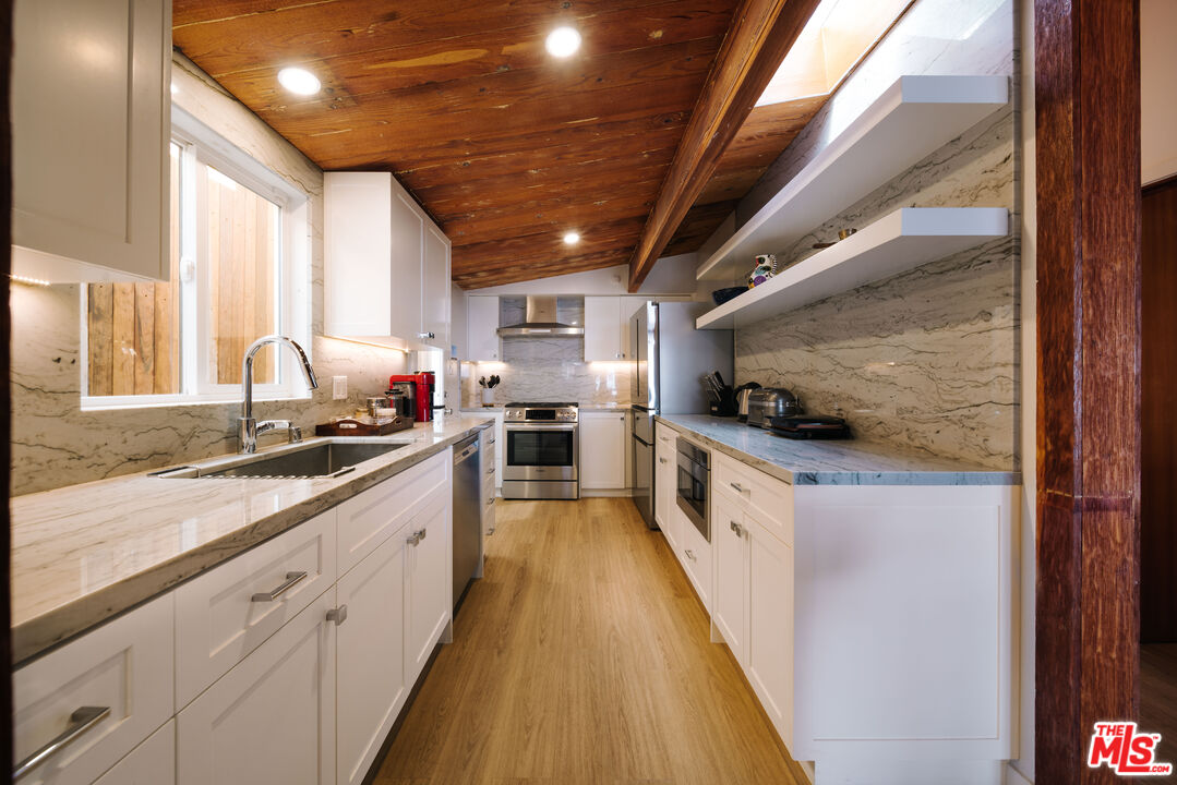 936 Palisades Beach Road Santa Monica, CA 90403 - Photo 7 of 31 a large kitchen with stainless steel appliances kitchen island granite countertop a large counter top a sink a stove and a refrigerator