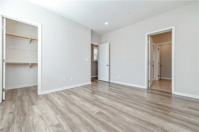 a view of an empty room with wooden floor and closet