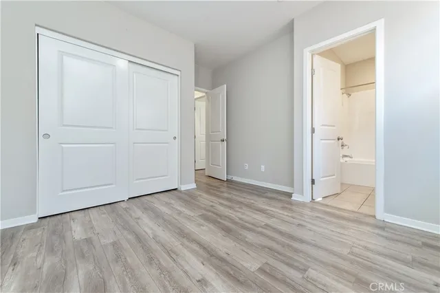 an empty room with wooden floor and closet area