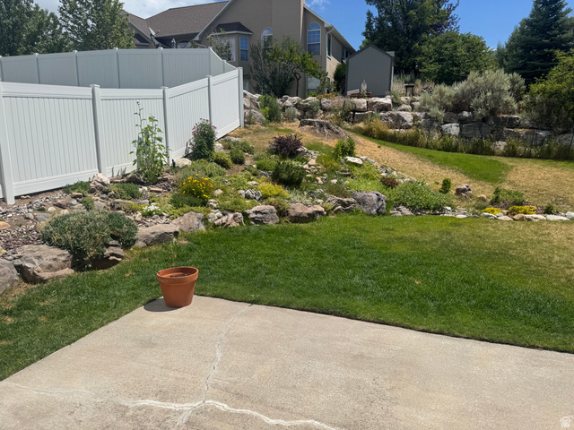 88 Canterbury Lane Logan, UT 84321 - Photo 37 of 37 Manicured lawn with a concrete patio, bordered by a white privacy fence and a rock garden