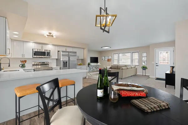 a kitchen with stainless steel appliances granite countertop a stove a refrigerator a kitchen island a table and chairs