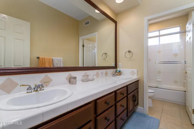 a bathroom with a double vanity sink a mirror and a bathtub