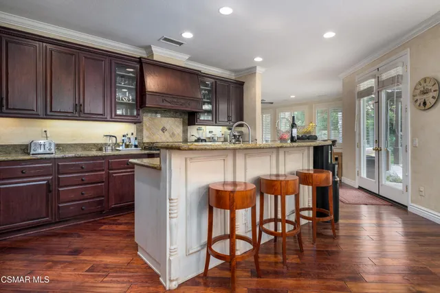 a kitchen with stainless steel appliances granite countertop wooden cabinets a dining table and chairs