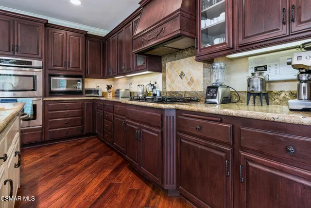 a kitchen with stainless steel appliances granite countertop wooden cabinets and a stove top oven