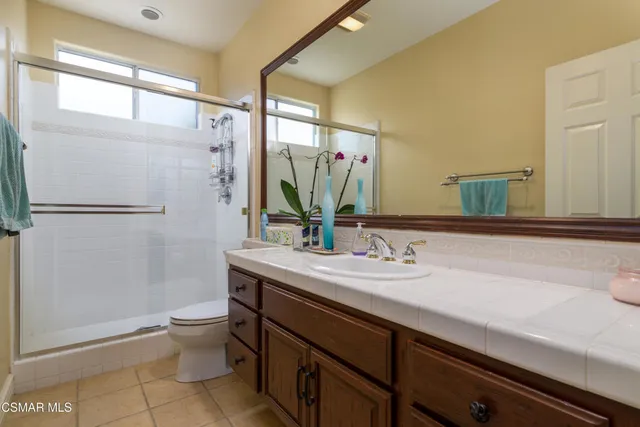 a bathroom with a granite countertop sink a toilet a mirror and shower