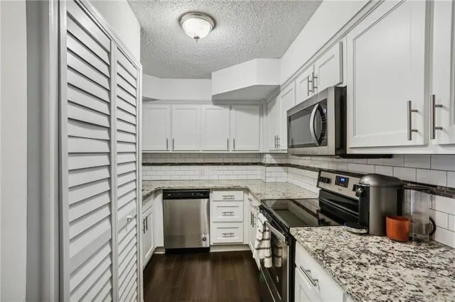 a kitchen with stainless steel appliances granite countertop a stove a sink and a microwave