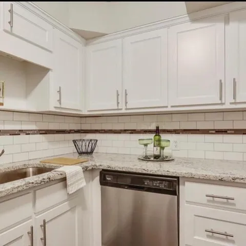 a kitchen with stainless steel appliances granite countertop a sink and a white cabinets