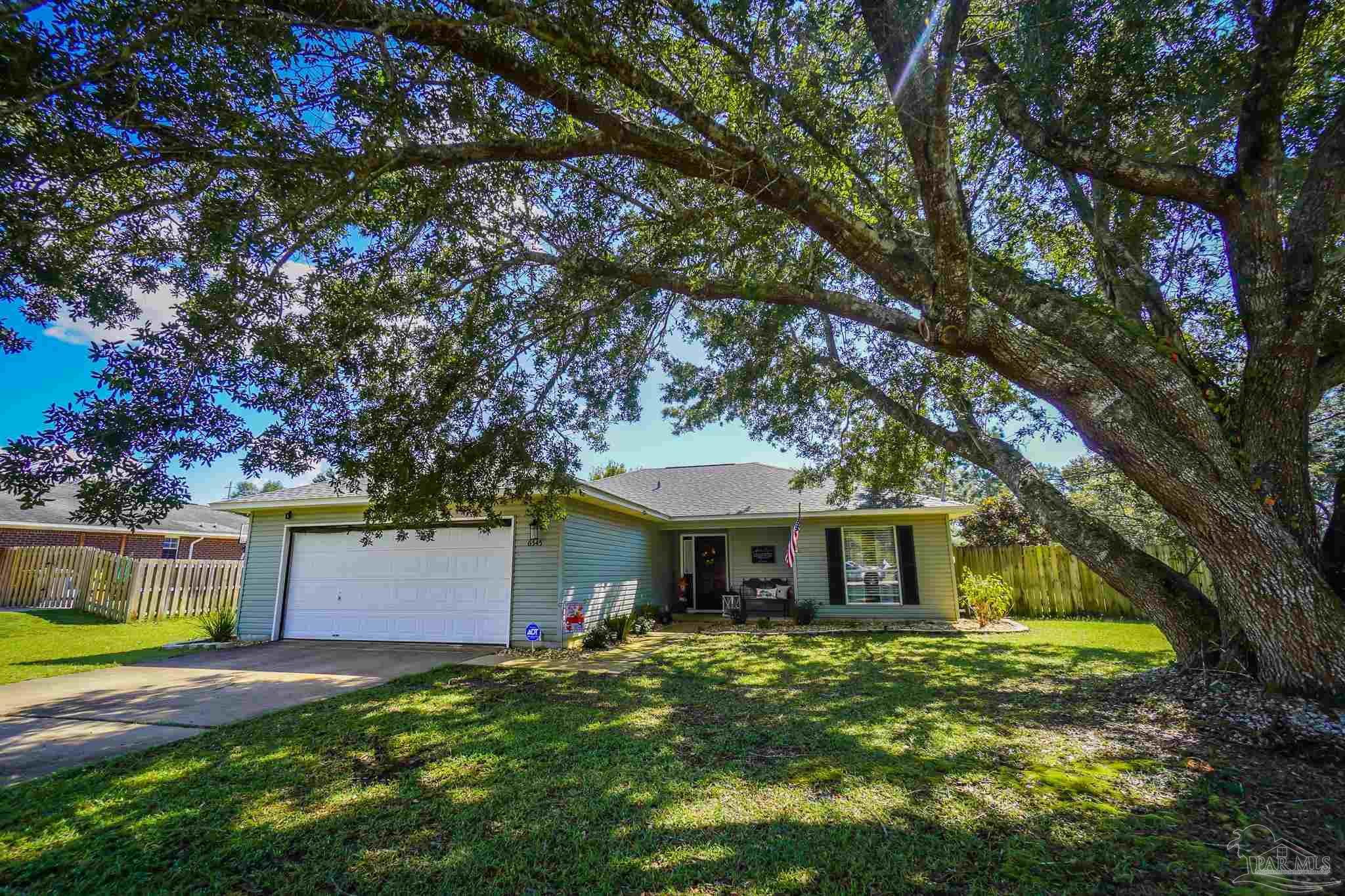 6545 Fern Street Navarre, FL 32566 - Photo 1 of 32 a front view of a house with a garden and trees