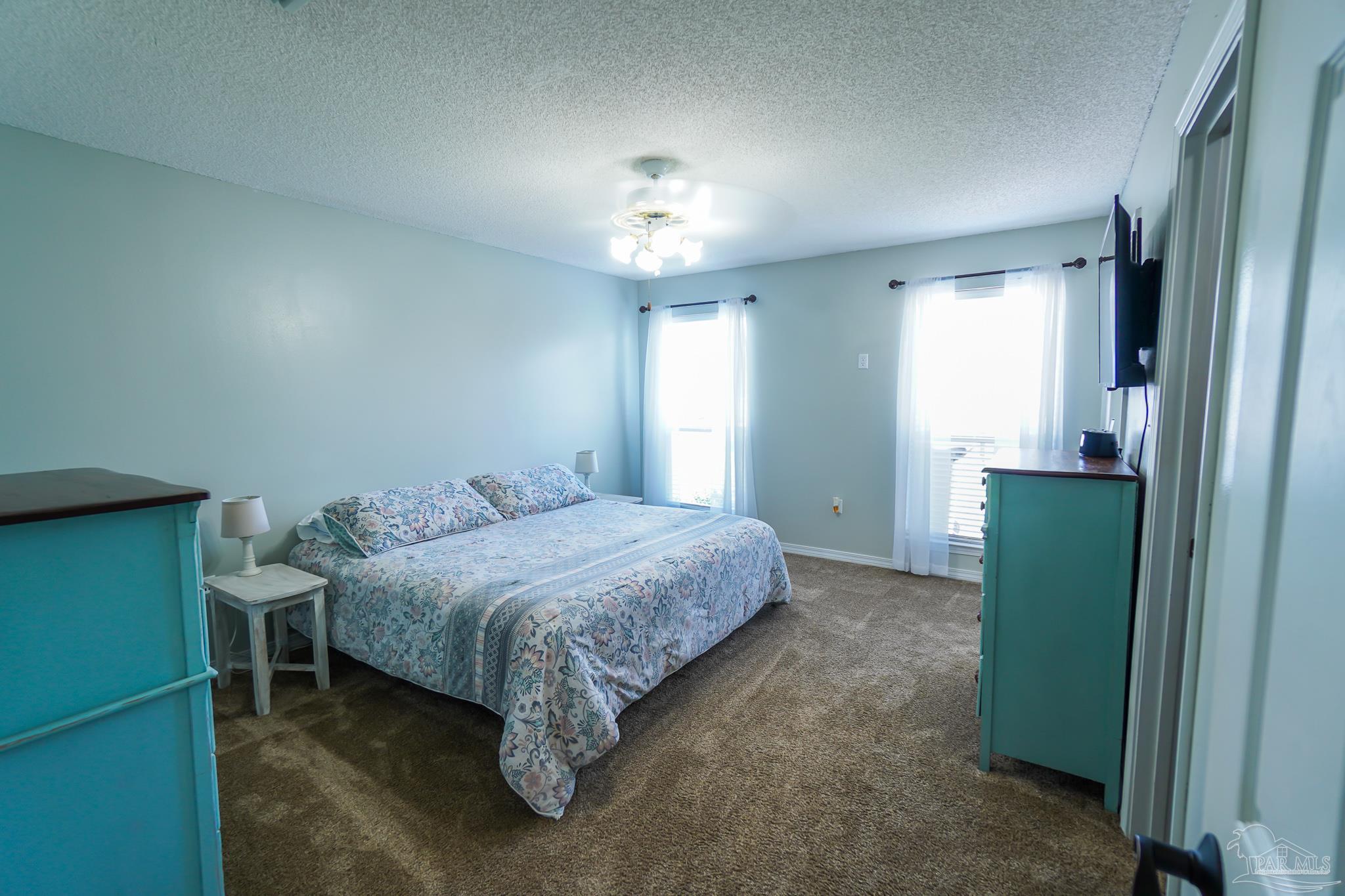 6545 Fern Street Navarre, FL 32566 - Photo 15 of 32 a bedroom with a bed and a chandelier