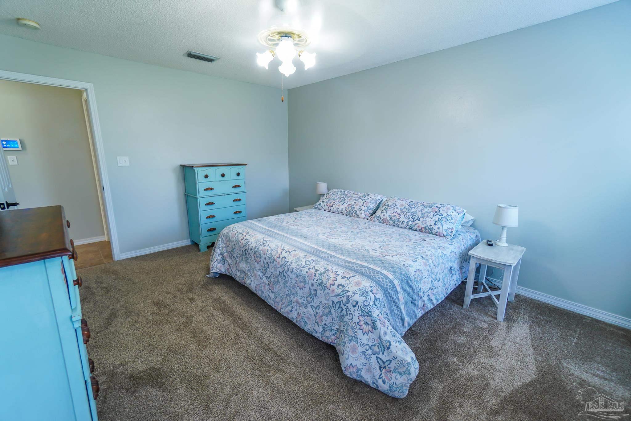 6545 Fern Street Navarre, FL 32566 - Photo 16 of 32 a bedroom with a bed and a chandelier