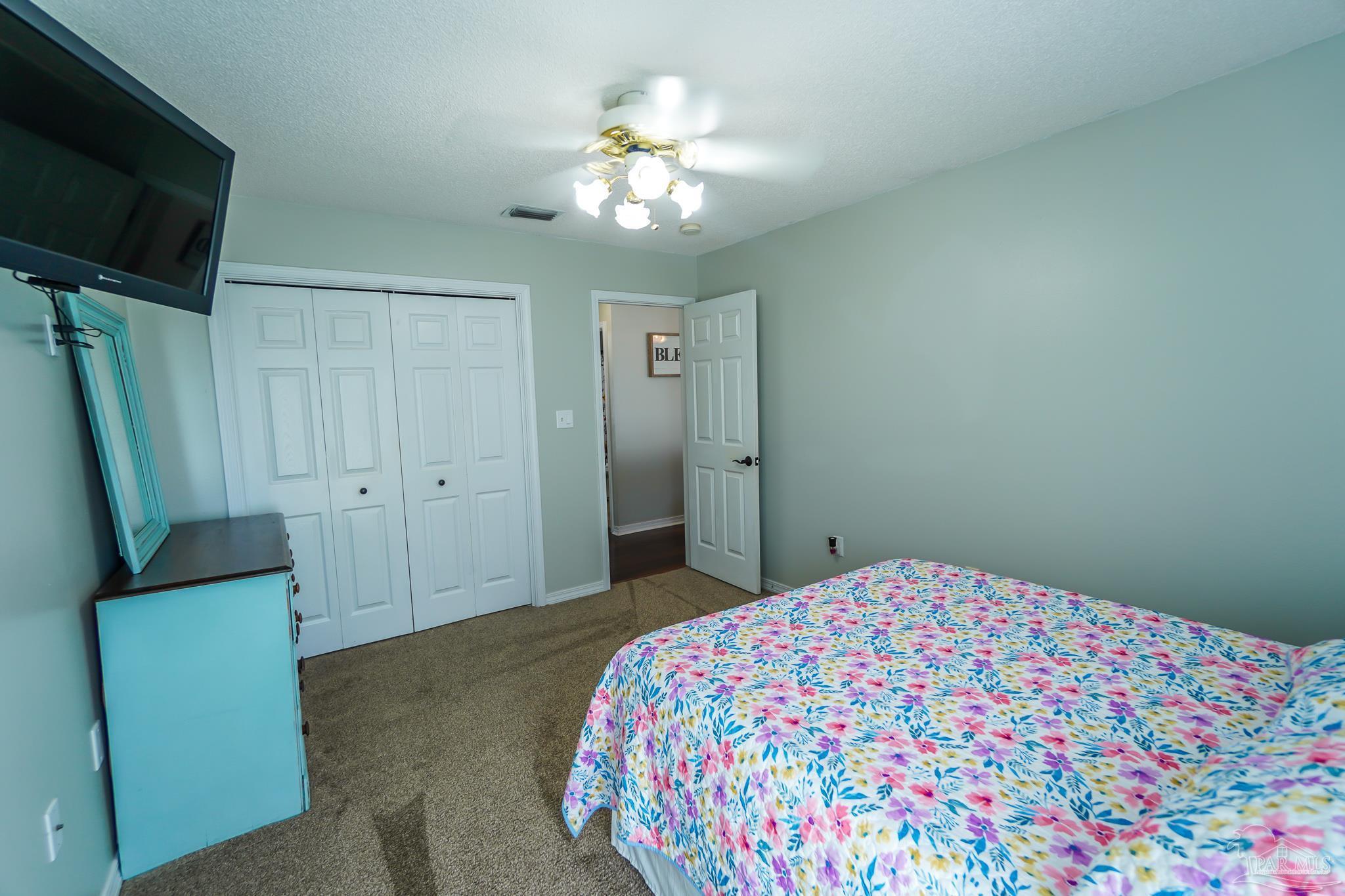 6545 Fern Street Navarre, FL 32566 - Photo 21 of 32 a bedroom with a bed and a chandelier