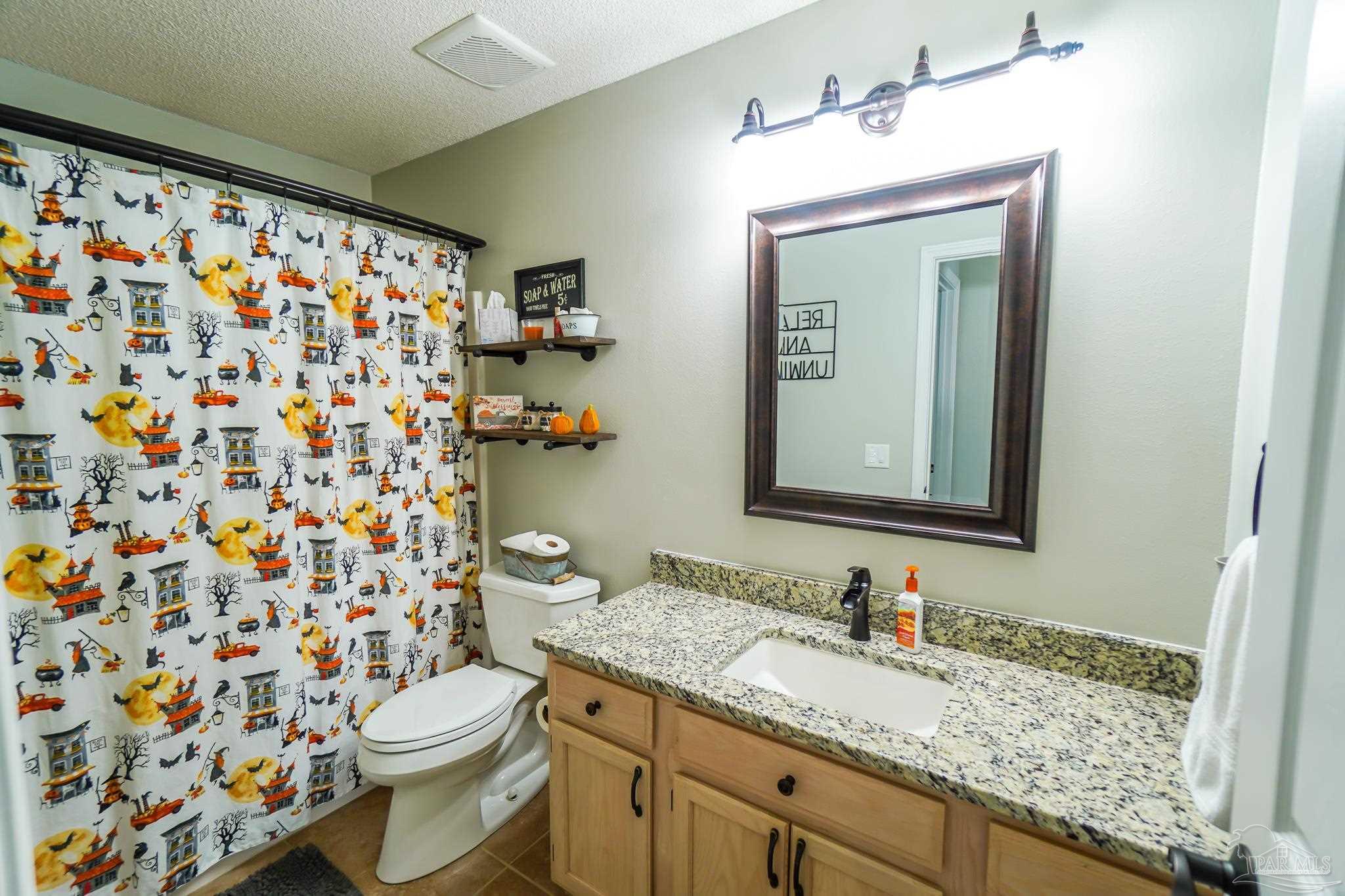 6545 Fern Street Navarre, FL 32566 - Photo 24 of 32 a bathroom with a granite countertop sink a toilet and a mirror