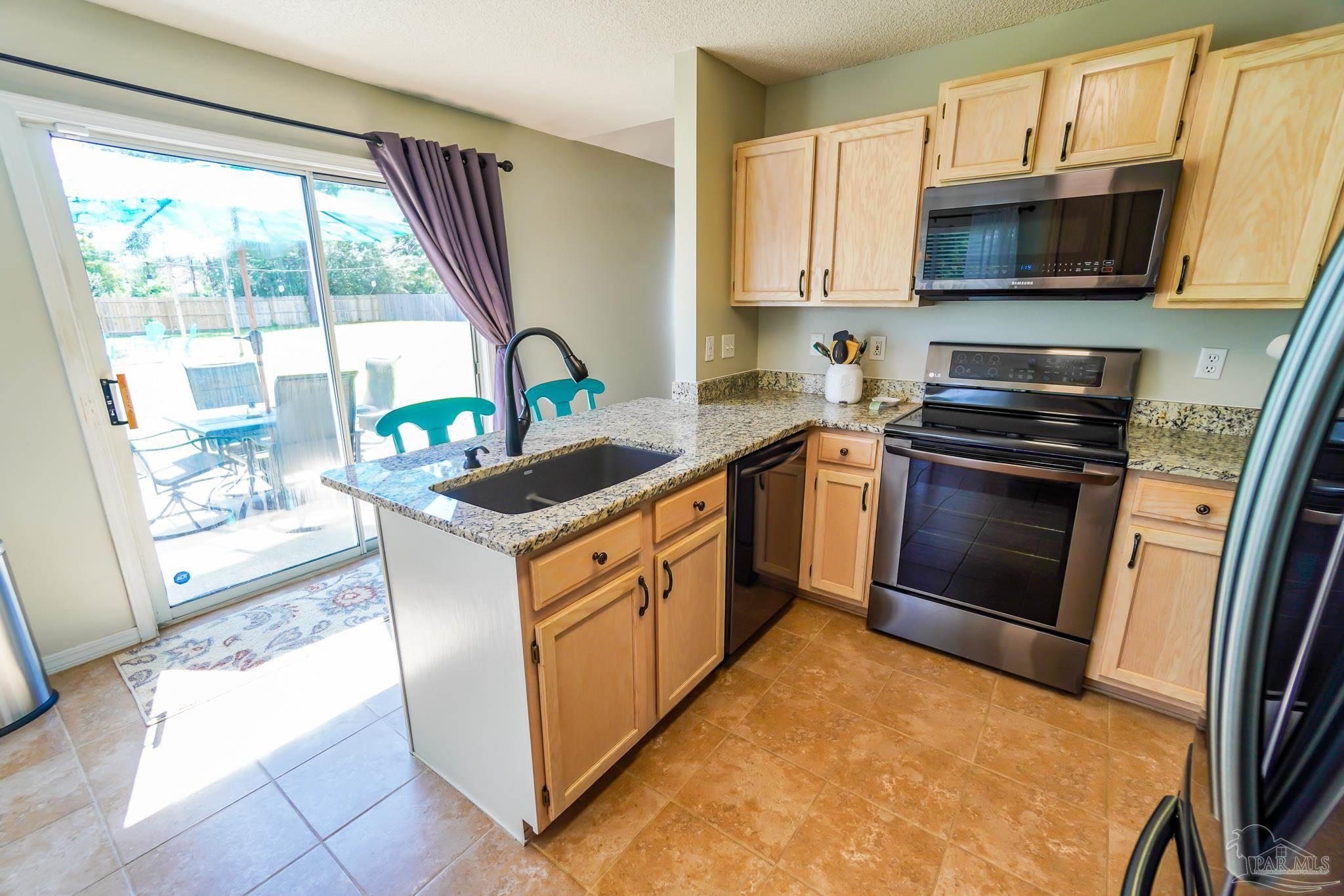 6545 Fern Street Navarre, FL 32566 - Photo 10 of 32 a kitchen with stainless steel appliances granite countertop a stove a sink and a microwave