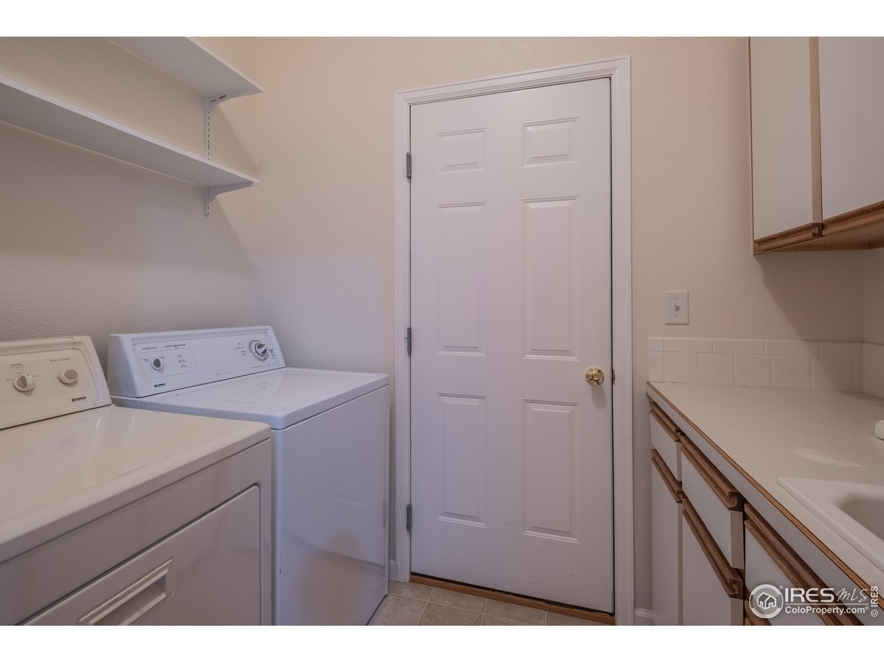 4313 29th Street Road Greeley, CO 80634 - Photo 20 of 31 Convenient main-level laundry with storage, utility sink, and exterior access-everyday chores made easy.