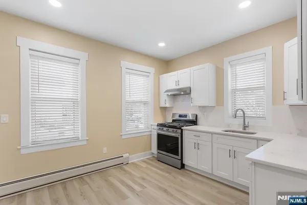 a kitchen with stainless steel appliances white cabinets and a stove top oven