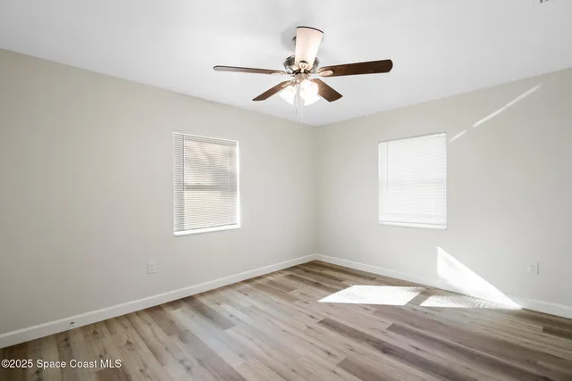 a view of empty room with wooden floor and fan