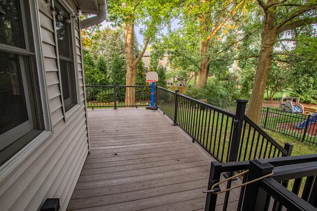 a view of a deck with wooden floor and fence next to a yard