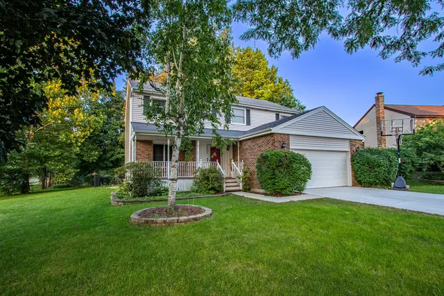 a view of a house with a yard and a large tree