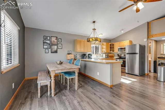 a kitchen with stainless steel appliances granite countertop a refrigerator a stove a sink dishwasher and a dining table with wooden floor