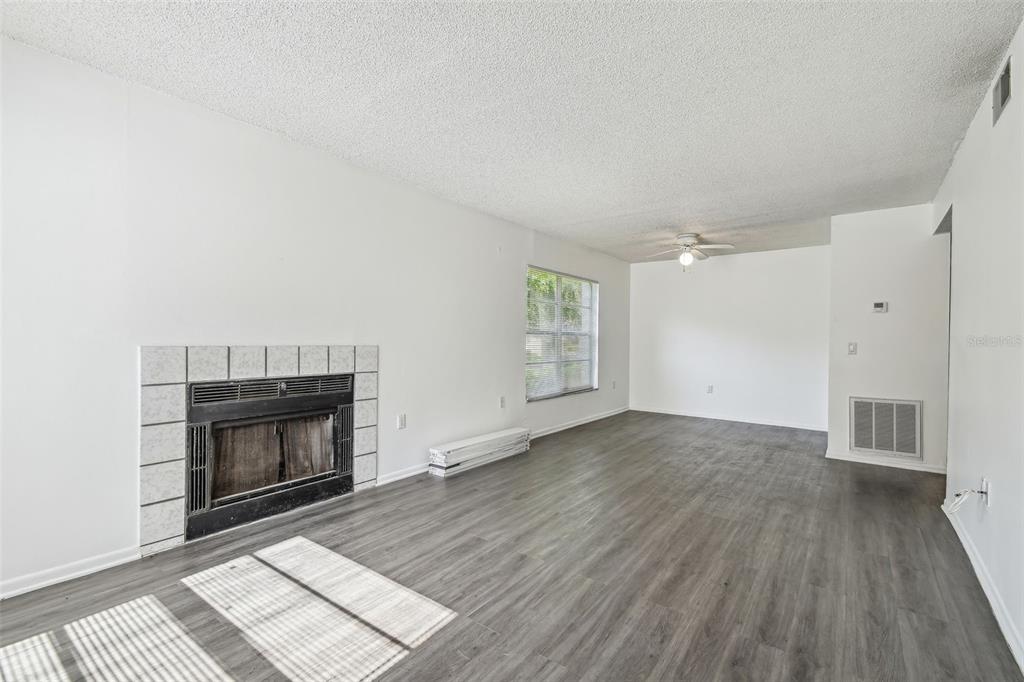 4208 Winding Moss Trail, Unit 102 Tampa, FL 33613 - Photo 7 of 27 an empty room with wooden floor fireplace and windows