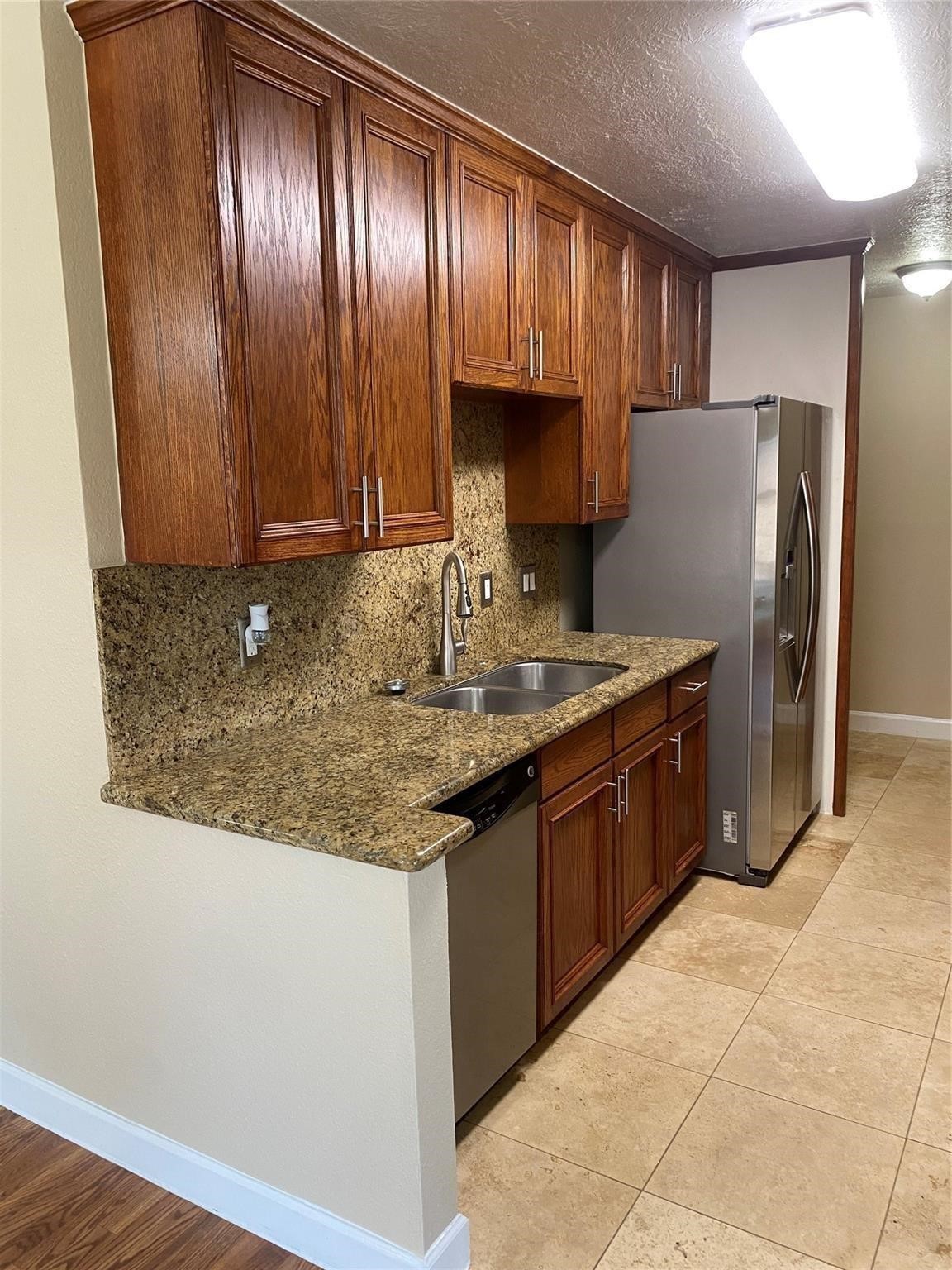 3226 Brookston Street Houston, TX 77045 - Photo 8 of 24 a kitchen with granite countertop wooden cabinets a refrigerator and a sink