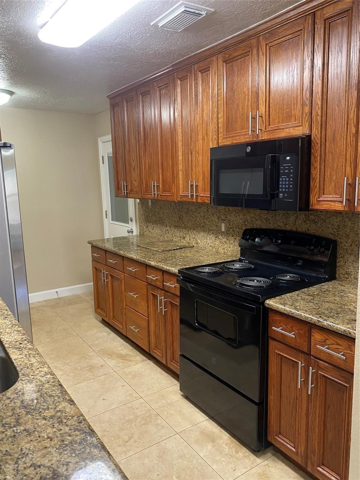 3226 Brookston Street Houston, TX 77045 - Photo 10 of 24 a kitchen with granite countertop wooden cabinets stainless steel appliances and a sink