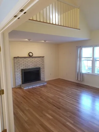 a view of empty room with wooden floor and fireplace