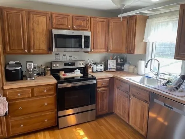 a kitchen with stainless steel appliances granite countertop a sink a stove a microwave oven cabinets and a counter top space