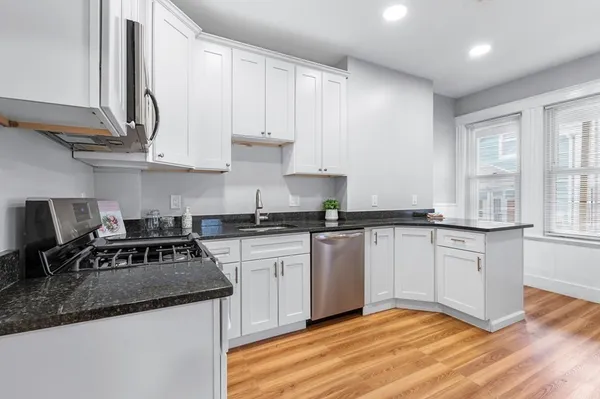 a kitchen with granite countertop a sink a stove and cabinets