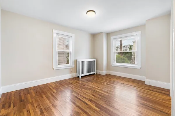 a view of an empty room with window and wooden floor