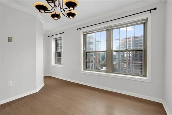 a view of an empty room with wooden floor and windows
