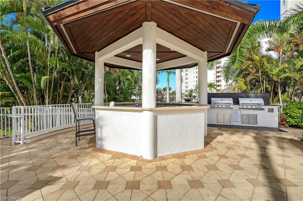 460 Launch Circle, Unit 403 Naples, FL 34108 - Photo 33 of 35 a view of a patio with a table and chairs under an umbrella with a small yard