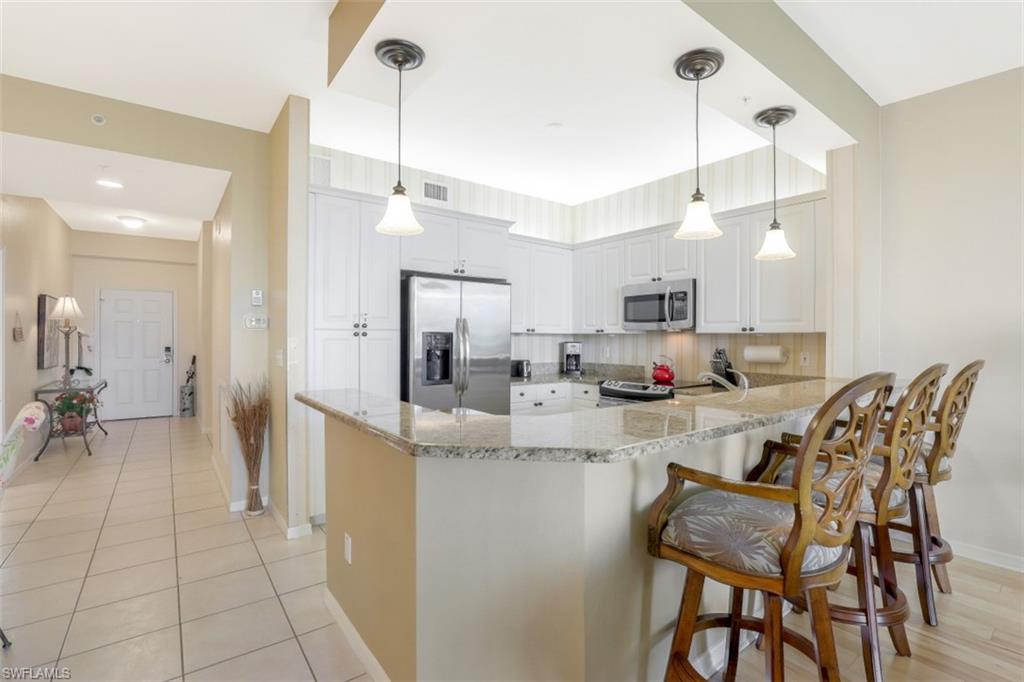 460 Launch Circle, Unit 403 Naples, FL 34108 - Photo 6 of 35 a kitchen with kitchen island a large counter top space appliances and cabinets
