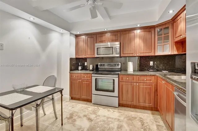 a kitchen with stainless steel appliances granite countertop a refrigerator a stove and a sink with cabinets