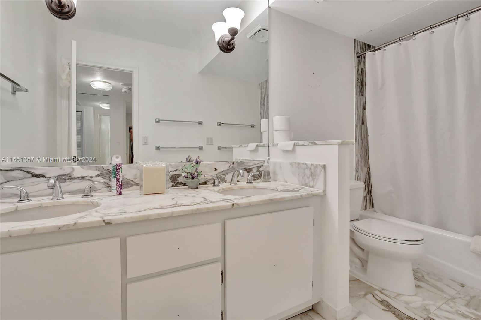 9801 Collins Avenue, Unit 3T Bal Harbour, FL 33154 - Photo 25 of 32 a bathroom with a granite countertop sink a toilet and a mirror