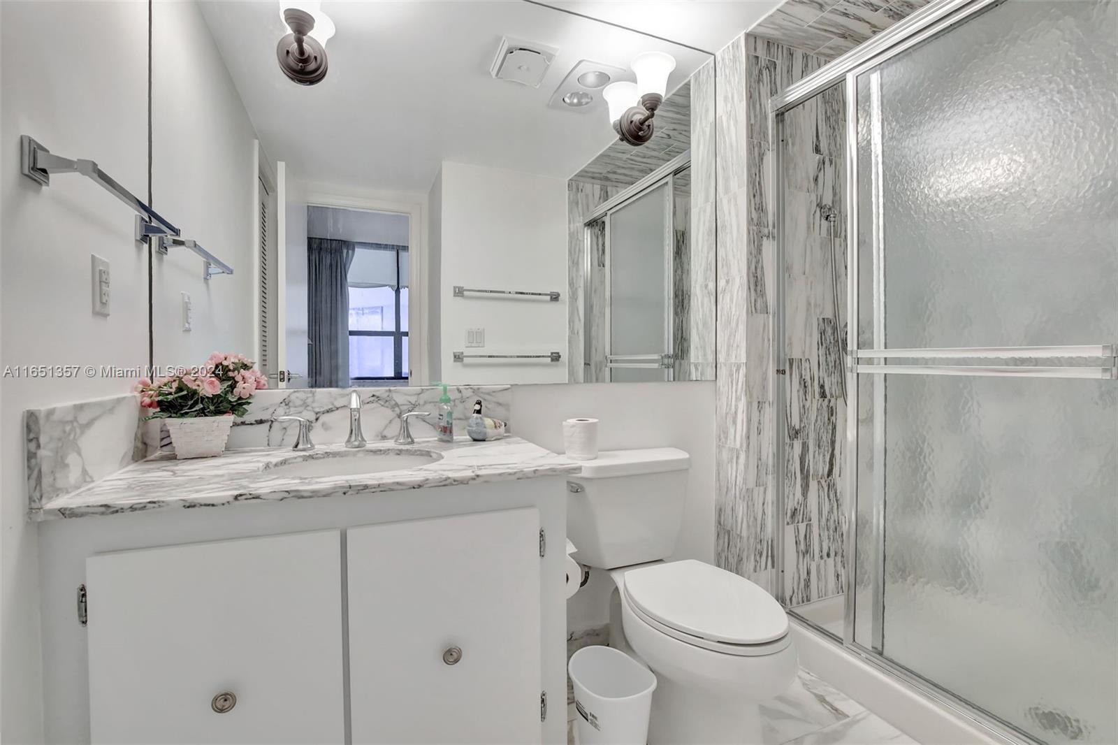 9801 Collins Avenue, Unit 3T Bal Harbour, FL 33154 - Photo 29 of 32 a bathroom with a granite countertop sink toilet a mirror a vanity and shower