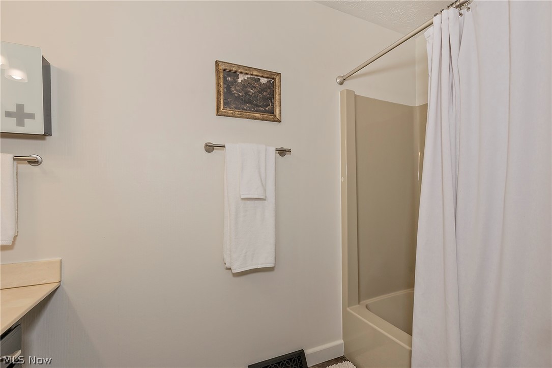 11292 Butternut Road Chardon, OH 44024 - Photo 28 of 49 Bathroom featuring a tub/shower combination with a light-colored surround, a wall-mounted towel bar, and a vanity with a light-toned countertop