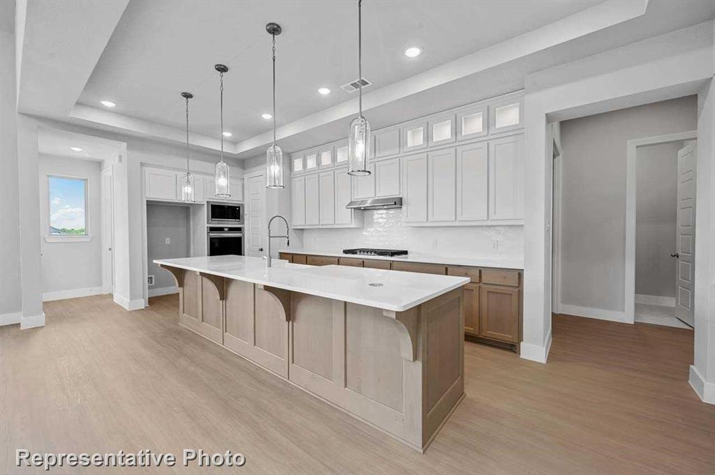 a large white kitchen with lots of counter space a sink appliances and cabinets