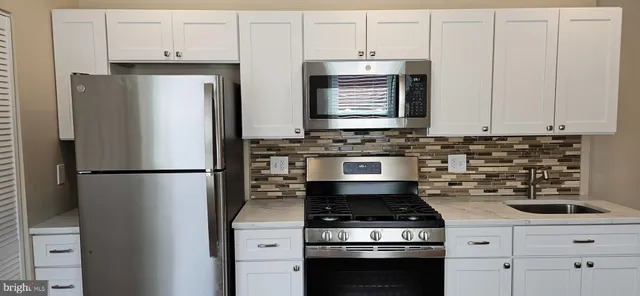 a kitchen with refrigerator a stove a sink and cabinets