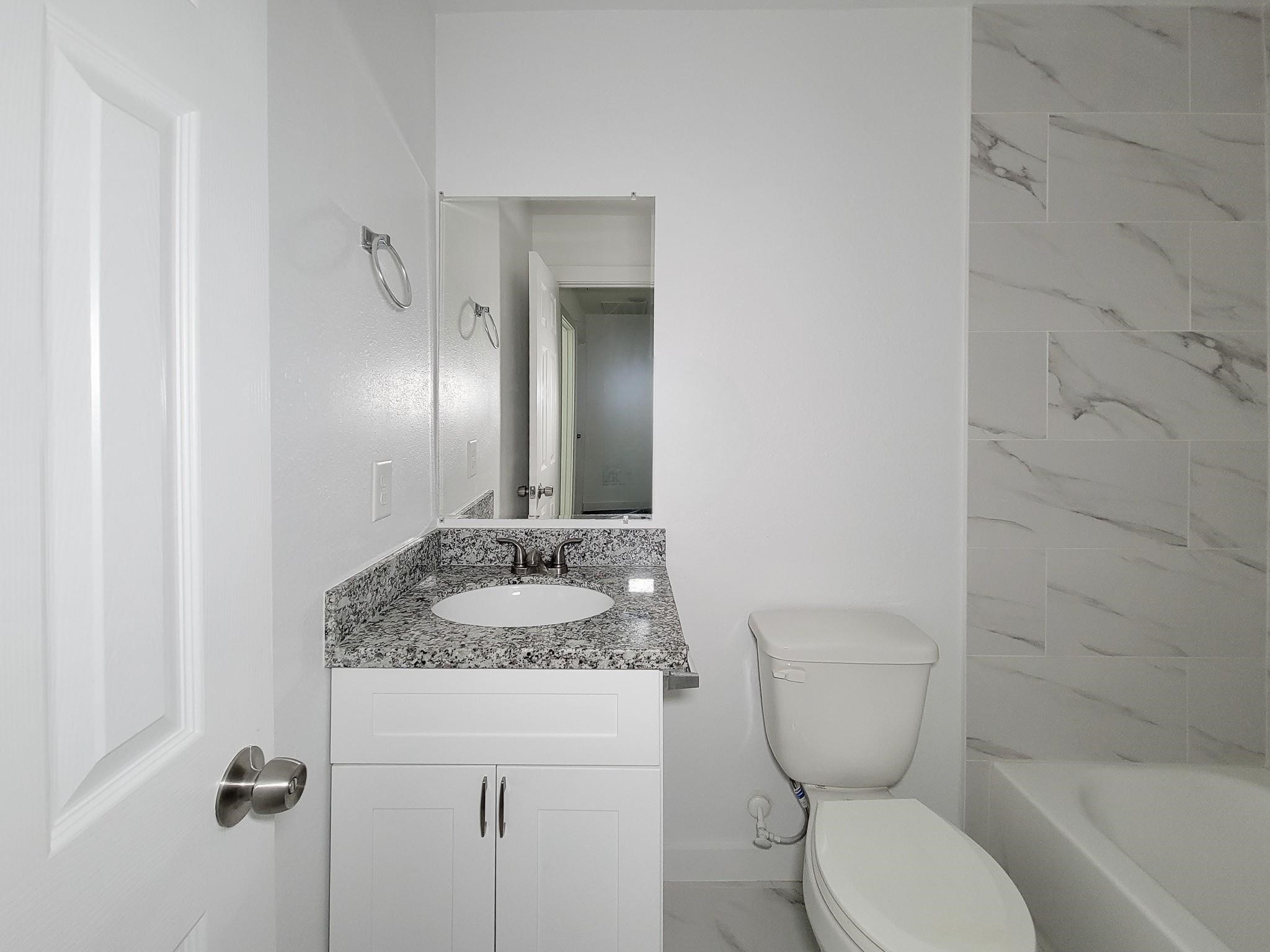 8122 Sterlingshire Street, Unit B Houston, TX 77078 - Photo 22 of 27 a bathroom with a granite countertop toilet a sink and a mirror