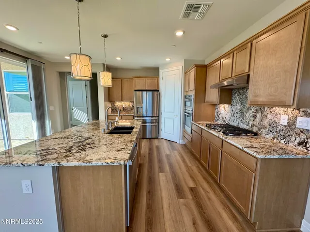 a kitchen with stainless steel appliances granite countertop a sink refrigerator and cabinets