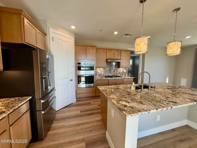 a kitchen with stainless steel appliances granite countertop a sink refrigerator and cabinets