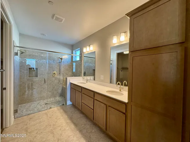 a bathroom with a double vanity sink mirror and shower
