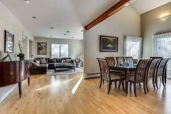 a view of dining room and livingroom with furniture wooden floor a rug a fireplace and a mirror