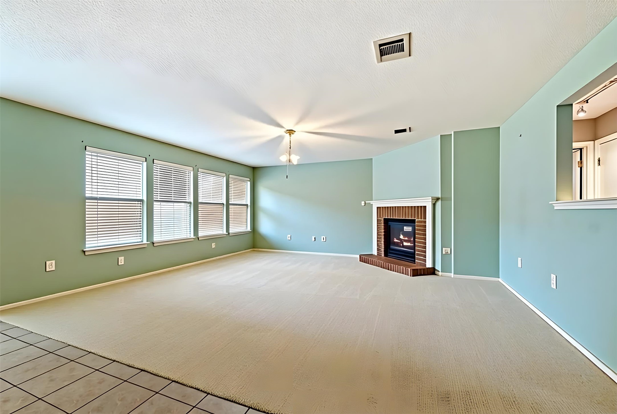4008 Springwillow Lane Round Rock, TX 78681 - Photo 2 of 29 Virtually staged - Living area featuring a brick fireplace, light tile patterned floors, light colored carpet, and a textured ceiling