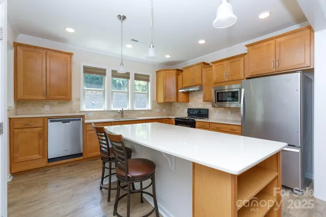 a kitchen with stainless steel appliances a stove a refrigerator white cabinets and wooden floor