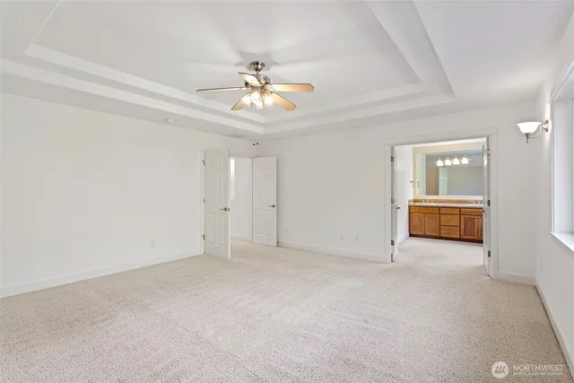 an empty room with chandelier fan and windows