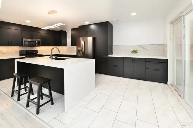 a view of a room with kitchen island stainless steel appliances wooden floor dining table and chairs