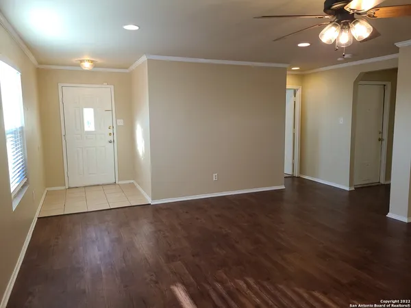 a view of an empty room with wooden floor and a window
